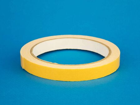 thin yellow duct tape lies on the blue backgroundの写真素材