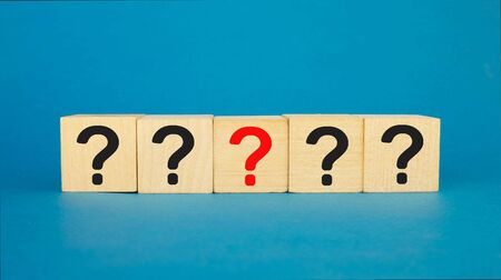 five question marks of which four are in black, and one in the center is in red. on a blue background.の写真素材
