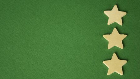 three wooden stars on a green background.