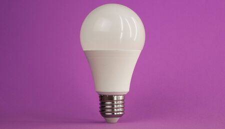 white light bulb on a purple background standing exactly up.