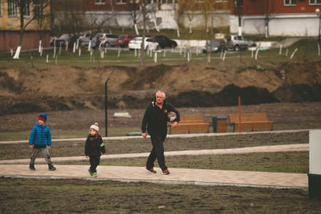 Grandpa with two toddlers goes to play football. moscow russia april 1 2020.のeditorial素材