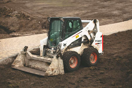 white excavator with a bucket on the construction site. Russia Moscow April 18 2020.のeditorial素材