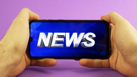 in men's hands phone with news on a purple background.の写真素材