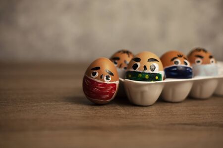 pack of eggs in masks on a wooden table. epidemic.の写真素材