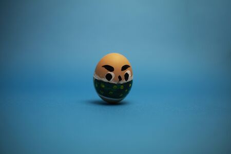 one egg with eyes and a mask on a blue background.の写真素材