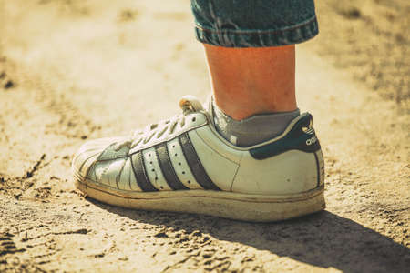 Russia Moscow April 20, 2020 women's feet in white old Adidas sneakersのeditorial素材