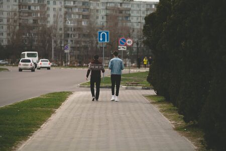 two friends are walking along a road in the city.の写真素材