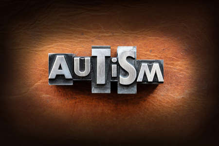The word Autism made from vintage lead letterpress type on a leather background.の写真素材