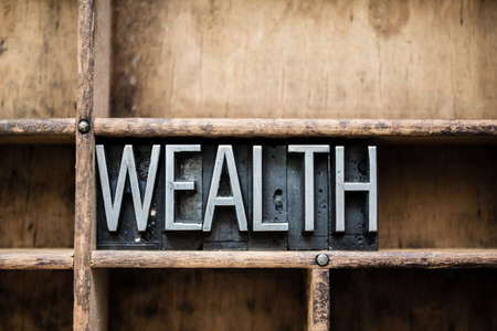 The word "WEALTH" written in vintage metal letterpress type in a wooden drawer with dividers.の写真素材
