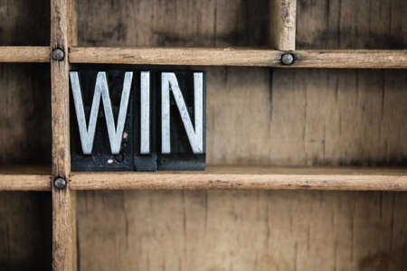 The word "WIN" written in vintage metal letterpress type in a wooden drawer with dividers.の写真素材