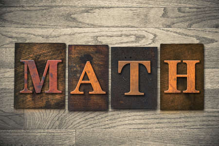 The word "MATH" theme written in vintage, ink stained, wooden letterpress type on a wood grained background.の写真素材