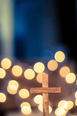 A wooden cross with defocused warm lights in the background.の写真素材