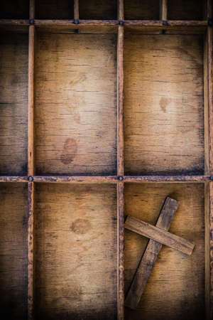 A wooden cross in a vintage wooden letterpress drawer.の写真素材