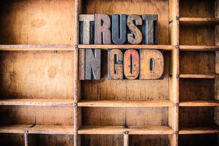 The words TRUST IN GOD written in vintage wooden letterpress type in a wooden type drawer.の写真素材