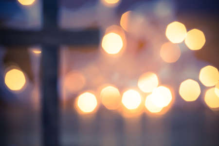 A wooden Christian cross with a soft bokeh lights background.