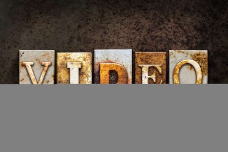 The word VIDEO written in rusty metal letterpress type on a dark textured grunge background.