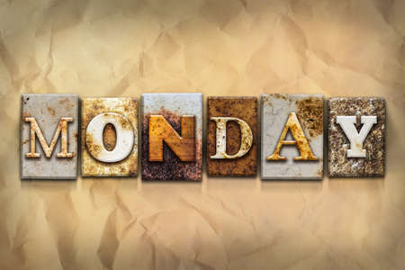 The word "MONDAY" written in rusty metal letterpress type on a crumbled aged paper background.の写真素材