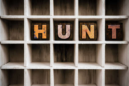 The word "HUNT" written in vintage ink stained wooden letterpress type in a partitioned printer's drawer.の写真素材
