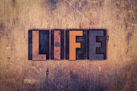 The word "Life" written in dirty vintage letterpress type on a aged wooden background.の写真素材