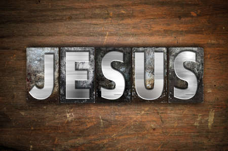 The word "Jesus" written in vintage metal letterpress type on an aged wooden background.の写真素材