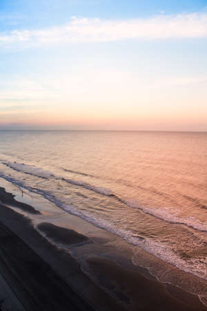 A colorful sunrise on the shoreline of a beach with a surf fisherman.の写真素材