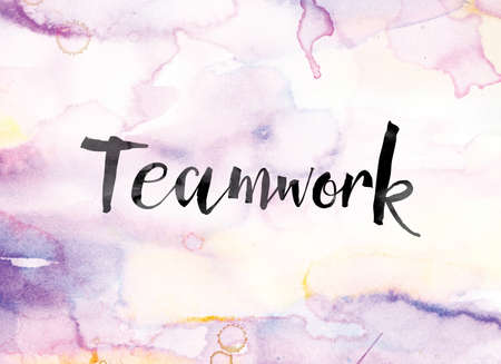 The word "Teamwork" painted in black ink over a colorful watercolor washed background concept and theme.の写真素材