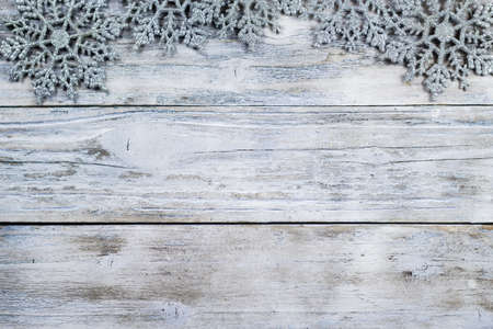 Christmas snow flake ornaments bordering vintage white washed wood background.の写真素材