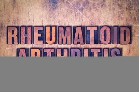 The words Rheumatoid Arthritis concept and theme written in vintage wooden letterpress type on a grunge background.の写真素材