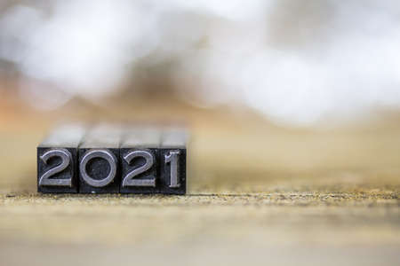 The year 2021 concept written in vintage retro metal letterpress type on a wooden background.の写真素材
