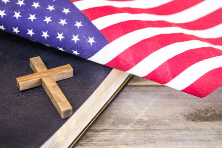 An American flag with a wooden Christian cross and a holy Bible on a wood background.の写真素材