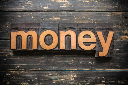 The word MONEY written in vintage wood letterpress type on a vintage rustic background.