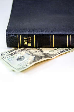A holy Christian bible with a twenty dollar bill isolated on a white background.の写真素材