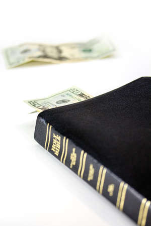 A holy Christian bible with a twenty dollar bill isolated on a white background.の写真素材