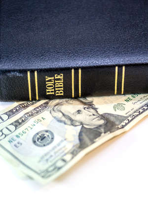 A holy Christian bible with a twenty dollar bill isolated on a white background.の写真素材