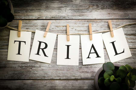 A set of printed cards spelling the word TRIAL on an aged wooden background.の写真素材