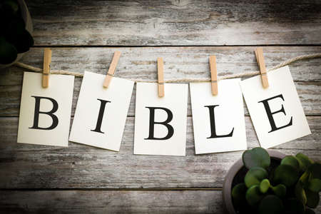 A set of printed cards spelling the word BIBLE on an aged wooden background.の写真素材