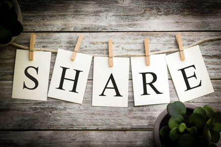 A set of printed cards spelling the word SHARE on an aged wooden background.の写真素材