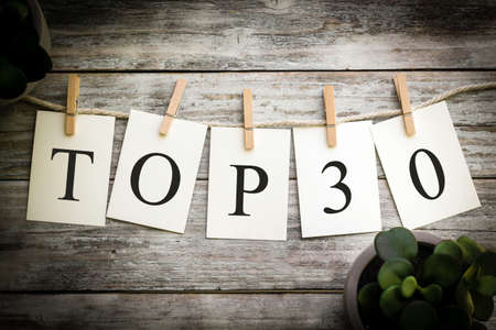 A set of printed cards spelling the words TOP 30 on an aged wooden background.の写真素材