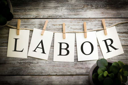 A set of printed cards spelling the word LABOR on an aged wooden background.の写真素材
