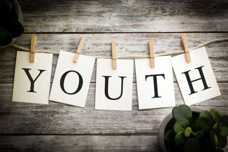 A set of printed cards spelling the word YOUTH on an aged wooden background.の写真素材