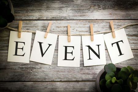 A set of printed cards spelling the word EVENT on an aged wooden background.の写真素材