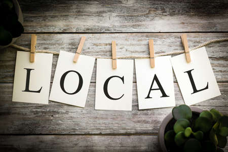 A set of printed cards spelling the word LOCAL on an aged wooden background.の写真素材