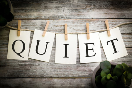 A set of printed cards spelling the word QUIET on an aged wooden background.の写真素材