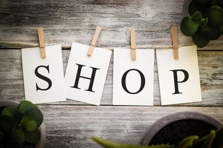 A set of printed cards spelling the word SHOP on an aged wooden background.の写真素材
