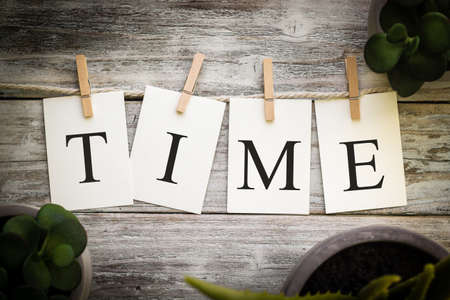 A set of printed cards spelling the word TIME on an aged wooden background.の写真素材