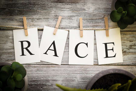 A set of printed cards spelling the word RACE on an aged wooden background.の写真素材