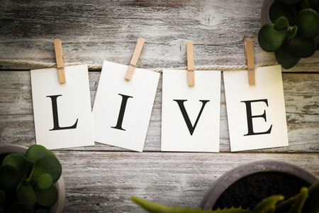A set of printed cards spelling the word LIVE on an aged wooden background.の写真素材