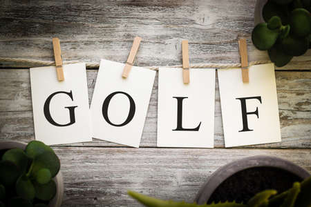 A set of printed cards spelling the word GOLF on an aged wooden background.の写真素材