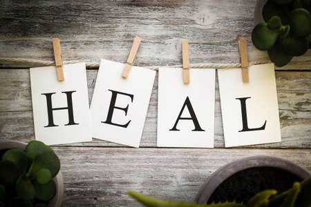 A set of printed cards spelling the word HEAL on an aged wooden background.の写真素材