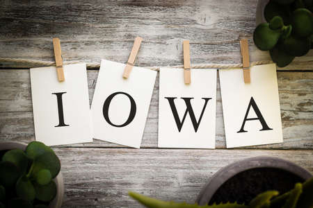 A set of printed cards spelling the word IOWA on an aged wooden background.の写真素材
